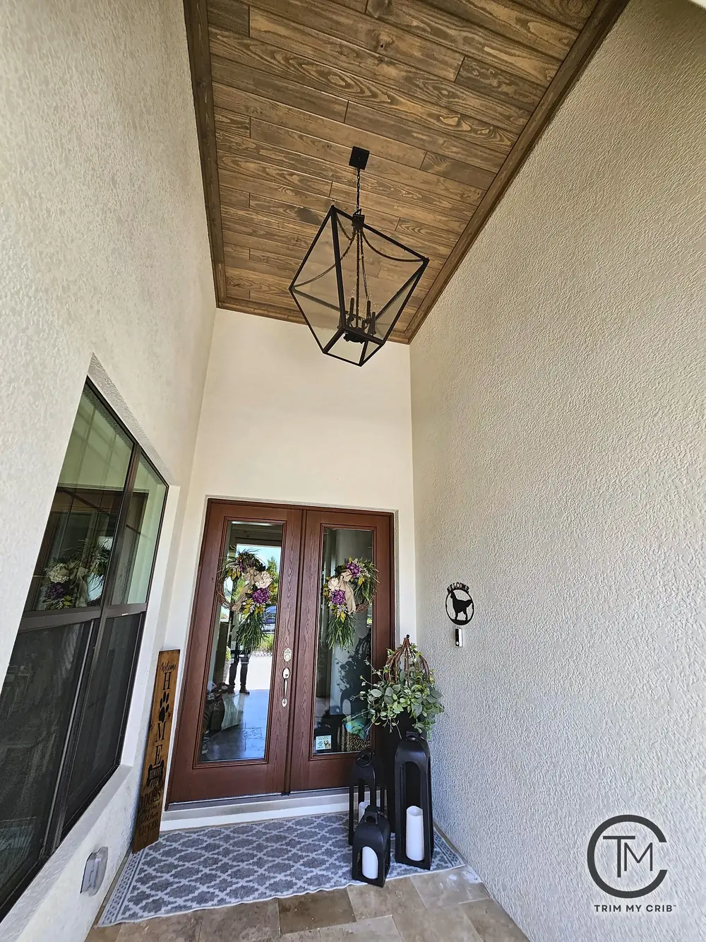 Tall entry porch with a stained wood ceiling and a black lantern pendant over double glass doors